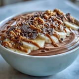 IndulgentChocolate Peanut Butter Smoothie Bowl in a white bowl, featuring chocolate chunks and frozen banana slices for a nourishing breakfast.
