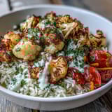 Overhead view of a healthy Roasted Cauliflower Bowl with colorful cherry tomatoes, cucumbers, carrots, and spinach piled high on steamed jasmine rice.