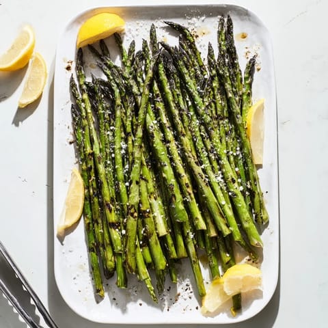 Freshly grilled asparagus spears lightly charred, garnished with lemon wedges.
