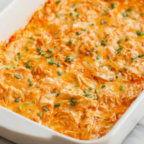 Golden, bubbly Buffalo Chicken Dip baked in a dish, topped with melted mozzarella and fresh chopped chives.