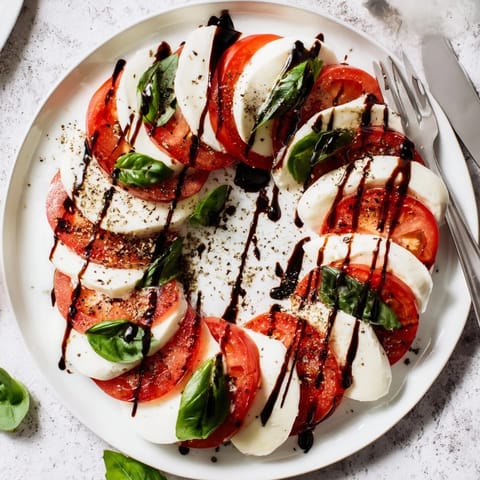 Freshly sliced tomatoes and creamy mozzarella topped with basil and drizzled balsamic glaze in a classic Caprese Salad.