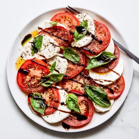 Bright Caprese Salad arranged on a platter with olive oil, sea salt, and fresh basil for a refreshing bite.