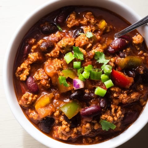 Hearty Turkey Chili simmering in a Dutch oven, featuring ground turkey, kidney beans, and diced peppers in a rich, spicy tomato broth.
