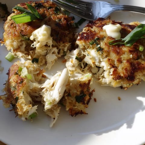 Pan-fried crab cakes garnished with fresh herbs, ready to serve alongside a creamy dipping sauce.