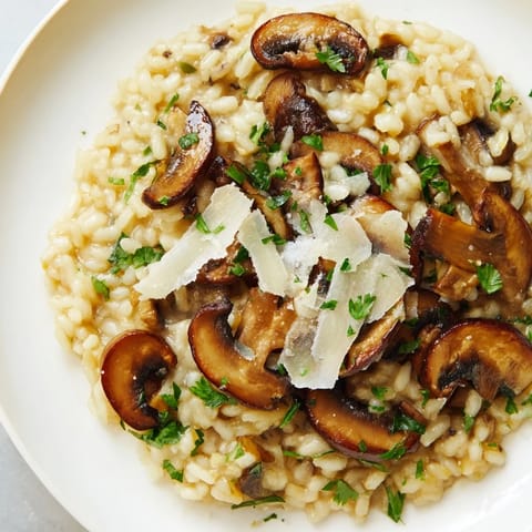 A comforting bowl of Roasted Mushroom Risotto garnished with thyme and extra Parmesan, ready to serve.