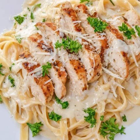 Cajun Chicken Alfredo served on a white plate, featuring fettuccine coated in rich Parmesan cream sauce.  
