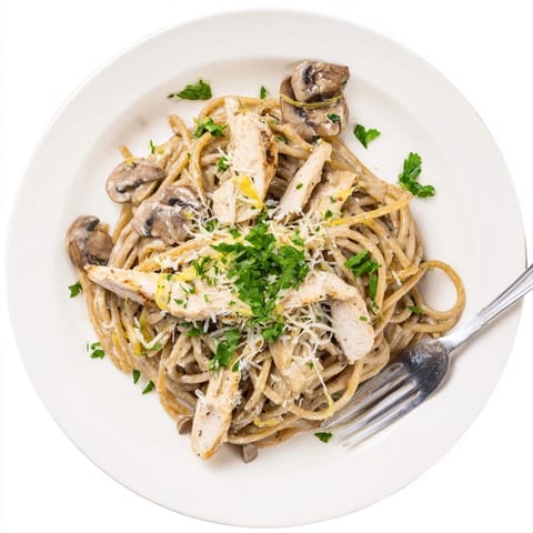 Creamy Mushroom Chicken Spaghettini is served in a warm bowl, featuring golden-brown chicken strips nestled in silky pasta coated with a rich, creamy mushroom sauce.