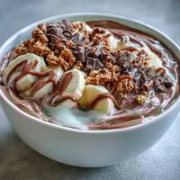 A creamy Chocolate Peanut Butter Smoothie Bowl topped with sliced banana, crunchy granola, and a rich peanut butter drizzle.